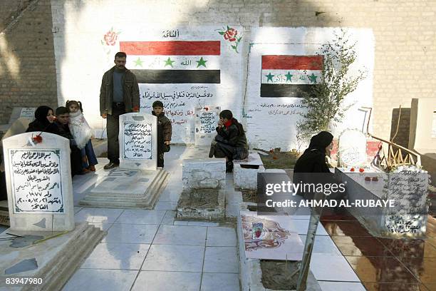 Iraqi Sunni Muslims wash the grave of loved ones and pray at the Ghazali cemetery in central Baghdad on the first day of the Eid al-Adha on December...