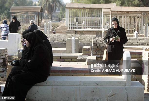 Iraqi Sunni Muslim woman prays at the graves of relatives at the Ghazali cemetery in central Baghdad on the first day of the Eid al-Adha on December...