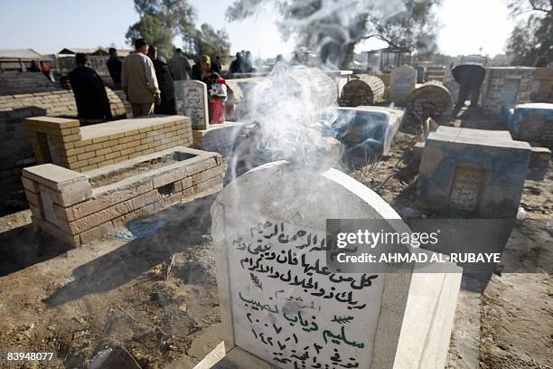 Incense burns on a grave as Iraqi Sunni Muslims visit the Ghazali cemetery in central Baghdad on the first day of the Eid al-Adha on December 08,...