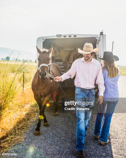 a man and a woman getting their horses out of a horse trailer. - horse trailer stock pictures, royalty-free photos & images