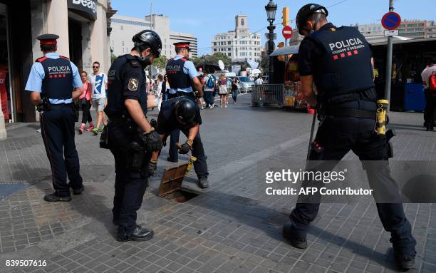 Catalan regional policemen, known as Mossos d'Esquadra check the area next to Plaza Catalunya before a march against terrorism which slogan will be...