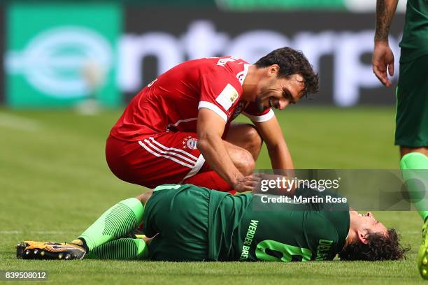 Mats Hummels of Bayern Muenchen checks on Thomas Delaney of Bremen after accidentally hitting him during the Bundesliga match between SV Werder...