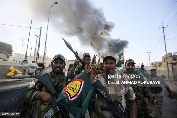 Fighters of the Hashed Al-Shaabi flash the victory gesture as they advance through a street in the town of Tal Afar, west of Mosul, after the Iraqi...