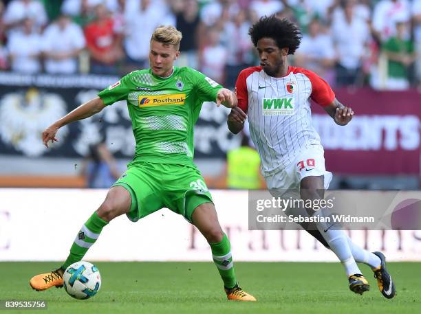 Nico Elvedi of Moenchengladbach fights for the ball with Caiuby of Augsburg during the Bundesliga match between FC Augsburg and Borussia...