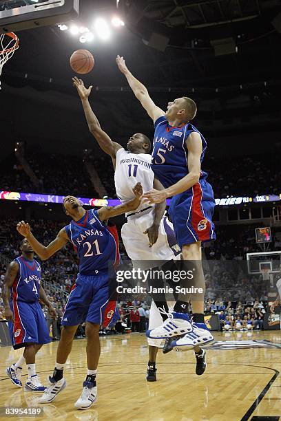 Matthew Bryan-Amaning of the Washington Huskies puts a shot up against Markieff Morris and Cole Aldrich of the Kansas Jayhawks during the CBE Classic...