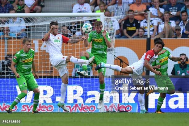 Jeffrey Gouweleeuw of Augsburg , Christoph Kramer of Moenchengladbach and Ja-Cheol Koo of Augsburg fight for the ball during the Bundesliga match...