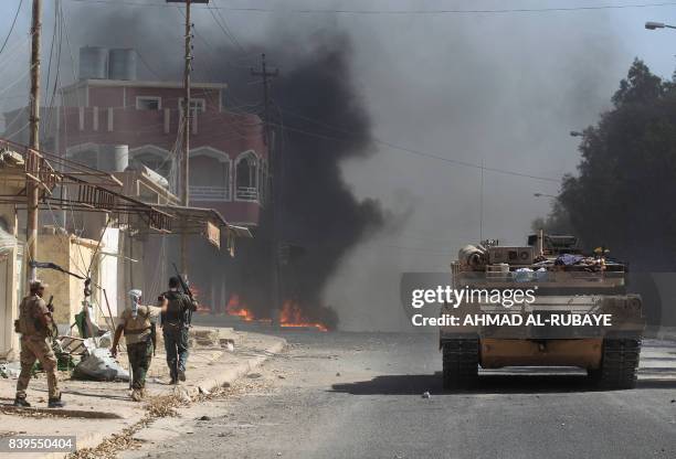 Smoke billows in the background as an Iraqi forces' tank advances through a street in the town of Tal Afar, west of Mosul, after the Iraqi government...