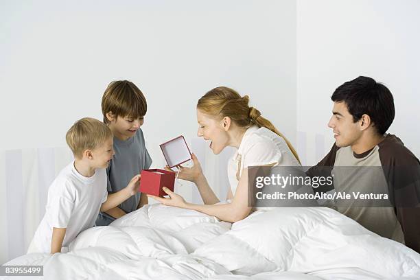 two boys giving mother present in bed, husband watching - open day 4 fotografías e imágenes de stock