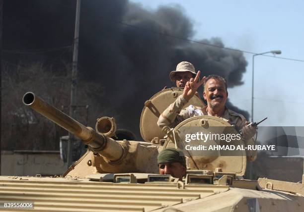 An Iraqi forces' officer flashes the victory gesture from the turret of an armoured vehicle during the advance through the town of Tal Afar, west of...