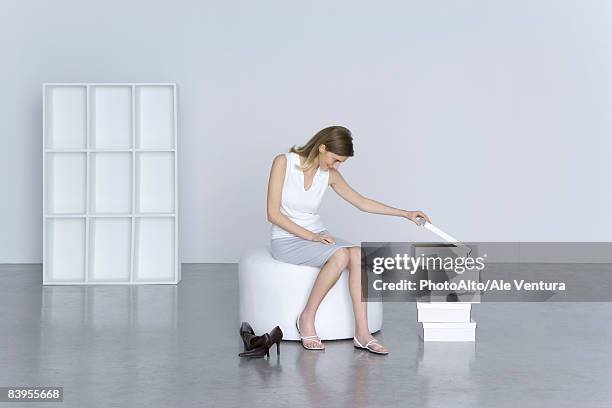 woman sitting beside stack of shoe boxes, peeking in top box - schuhkarton stock-fotos und bilder