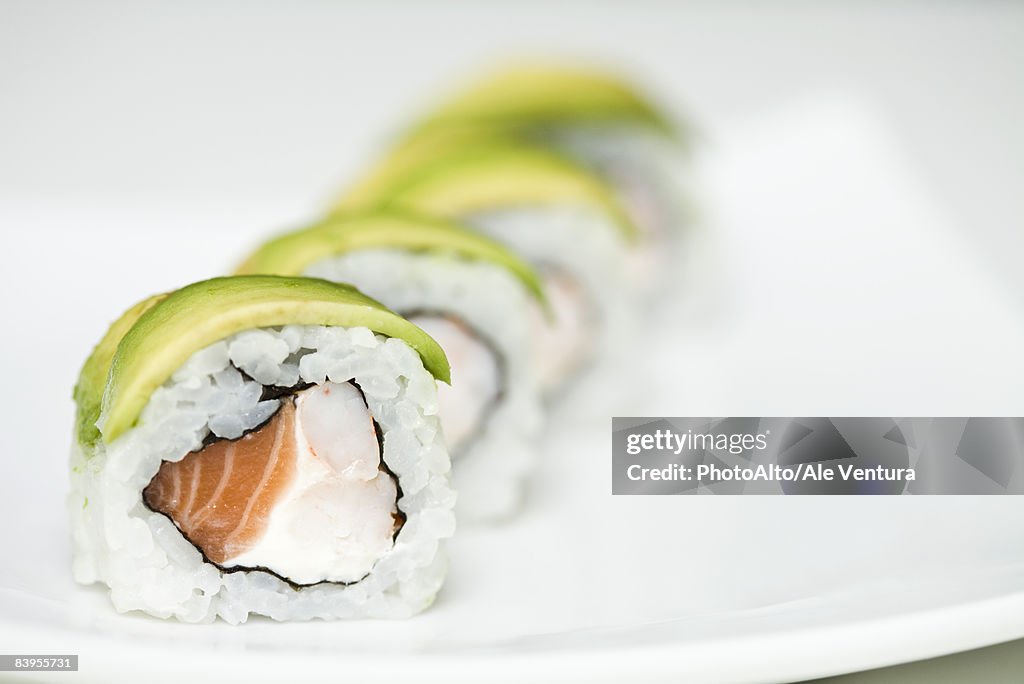 Row of maki sushi on sushi plate, close up
