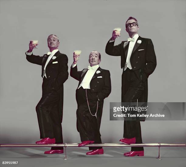 Toast made by three men of varying heights and type, all wearing tuxedos and bright red patent leather shoes, ca.1950s. United States.