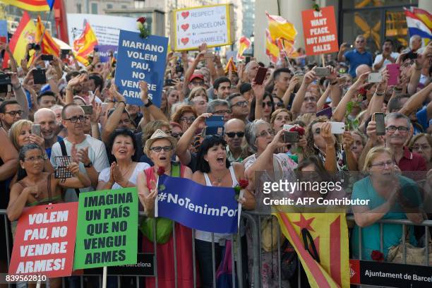 People hold placards reading in Catalan "No Tinc Por" and "You want peace, don't sell weapons" during a march against terrorism in Barcelona on...