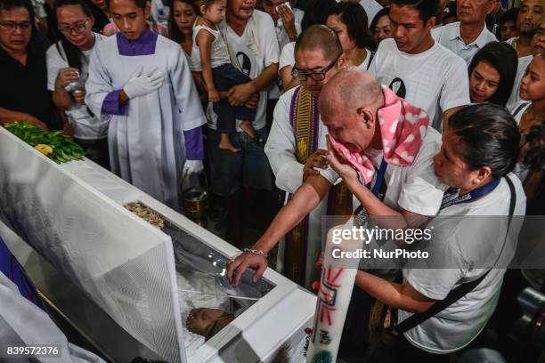 The parents and relatives of Kian Loyd Delos Santos weep over his coffin during his funeral rites in Caloocan, Metro Manila, Philippines, August 26,...