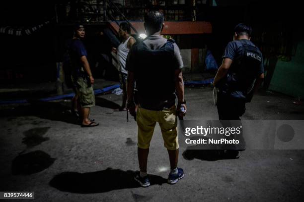 Policemen in plainclothes patrol a dark alley near the scene where 3 men were killed during a police operation against illegal drugs in Caloocan,...