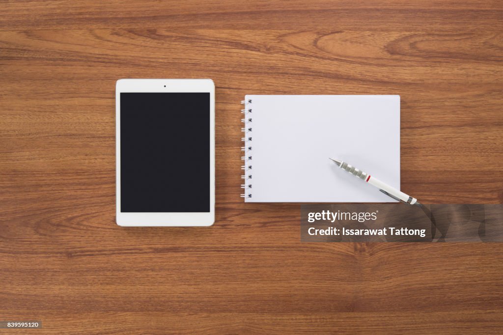 Tablet, notebook and pen on wooden desk, Top view