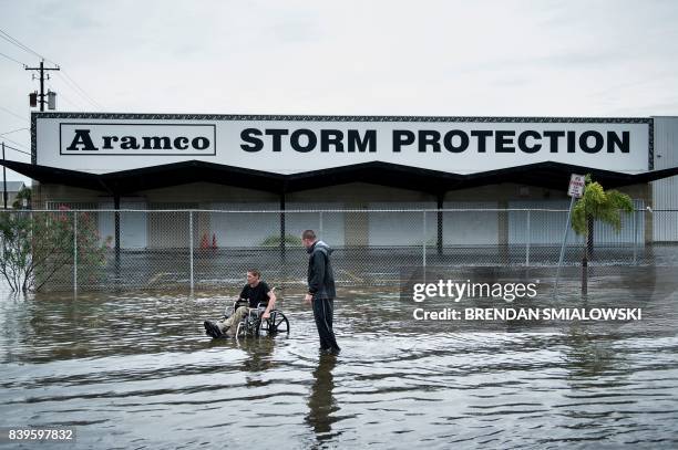 Brad Matheney offers help to a man in a wheelchair in a flooded street while Hurricane Harvey passes through Texas August 26, 2017 in Galveston,...