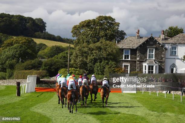The field heads down the back straight during the Station Yard Garage Handicap Steeplechase race at Cartmel Races at Cartmel Racecourse on August 26,...