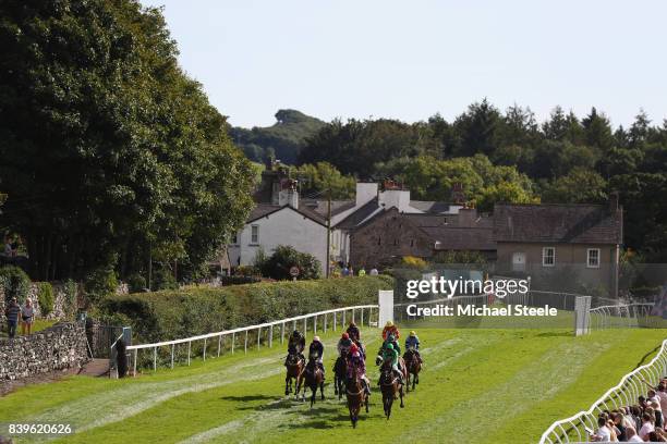 The field heads down the back straight during the Station Yard Garage Handicap Steeplechase race at Cartmel Races at Cartmel Racecourse on August 26,...