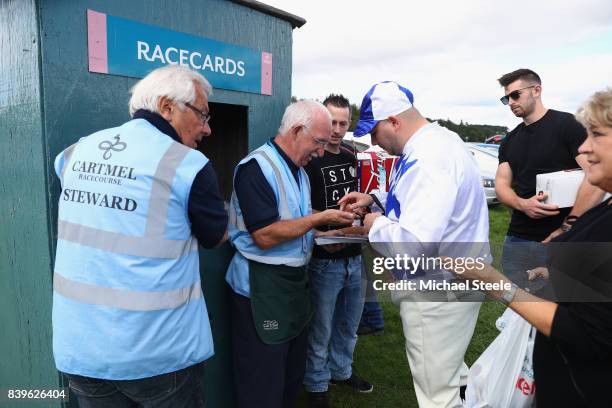 Racegoer dreed as a jockey purchases a racecard during Cartmel Races at Cartmel Racecourse on August 26, 2017 in Cartmel, Cumbria.