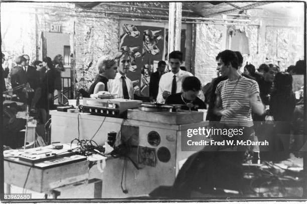 American fashion model and actress Edie Sedgwick and photographer Billy Name stand with unidentified others on either side of the dj 'booth' during a...
