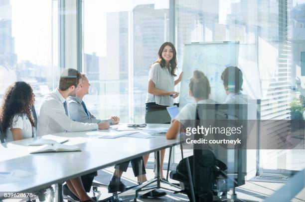 mujer dando una presentación a su equipo. - empresarios fotografías e imágenes de stock