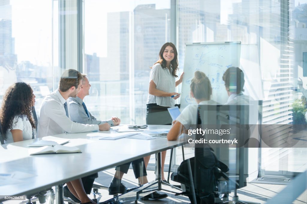 Mulher dando uma apresentação para sua equipe.