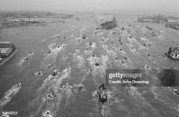 Royal Navy aircraft carrier, possibly HMS Hermes, is met by a flotilla of small vessels on its return to Portsmouth from the south Atlantic after the...