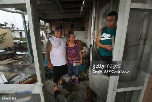 Members of the Martinez family return to find their home badly damaged after Hurricane Harvey hit Rockport, Texas on August 26, 2017. / AFP PHOTO /...