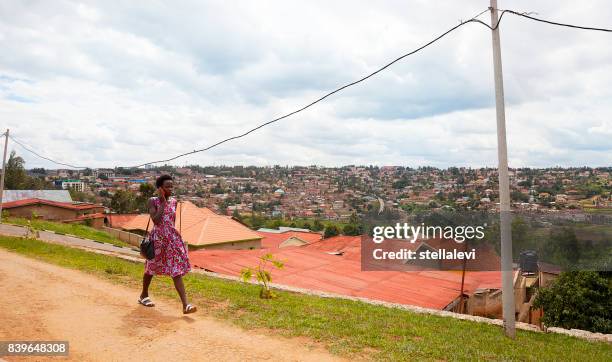 woman on cell phone outdoors with view of rooftops an houses. kigali. - kigali stock pictures, royalty-free photos & images