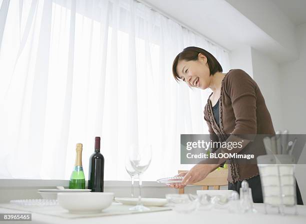 mature woman setting the table - homemaker stock-fotos und bilder