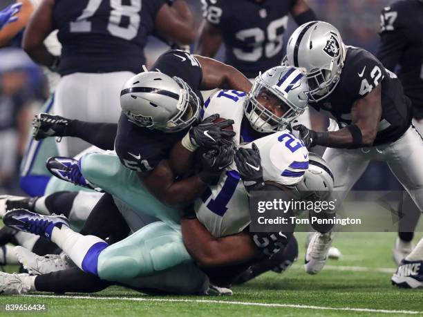 Ezekiel Elliott of the Dallas Cowboys gets tackled by Bruce Irvin, Jelani Jenkins , and Karl Joseph of the Oakland Raiders in the first quarter of a...
