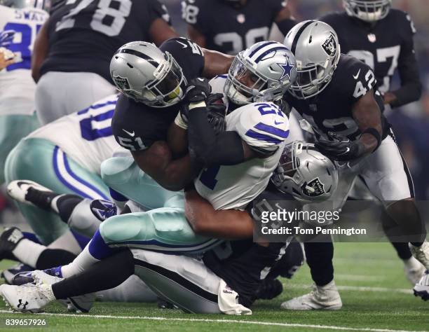 Ezekiel Elliott of the Dallas Cowboys gets tackled by Bruce Irvin, Jelani Jenkins, and Karl Joseph of the Oakland Raiders in the first quarter of a...