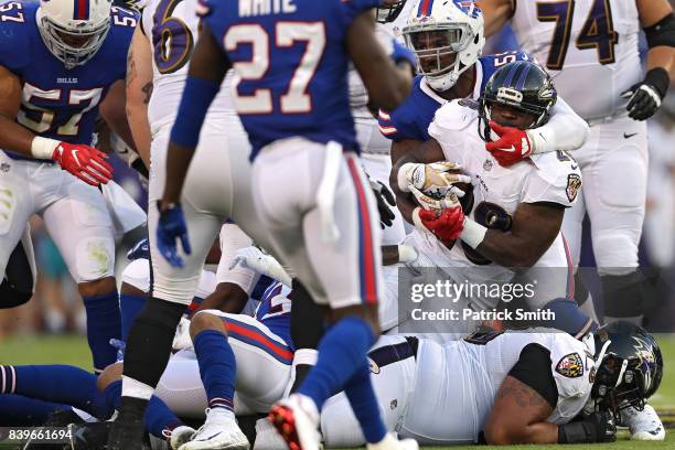 Running back Terrance West of the Baltimore Ravens is tackled by multiple Buffalo Bills defenders in the first half during a preseason game at M&T...