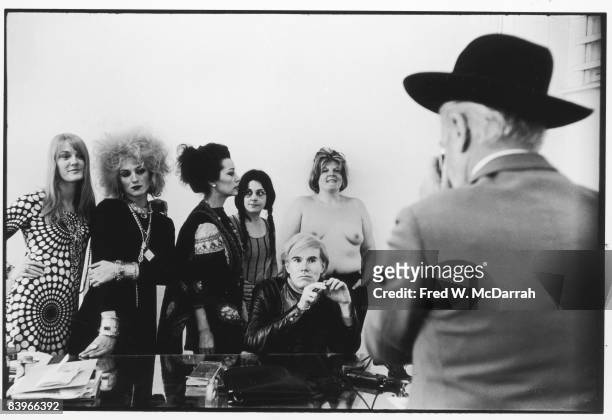 View over the shoulder of British fashion photographer Cecil Beaton as he photographs American pop artist Andy Warhol and, standing from left, Ingrid...