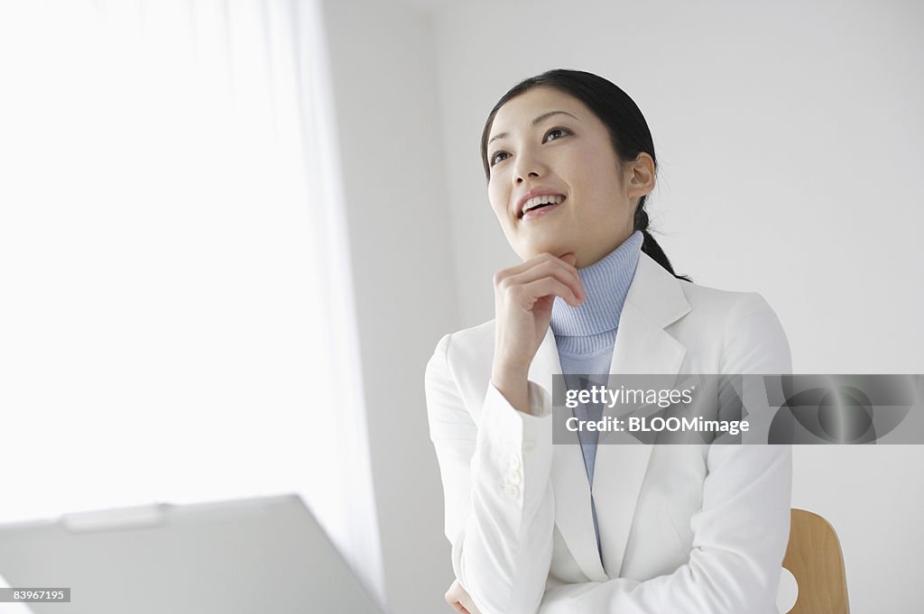 Woman using PC, smiling, resting her chin on her hand