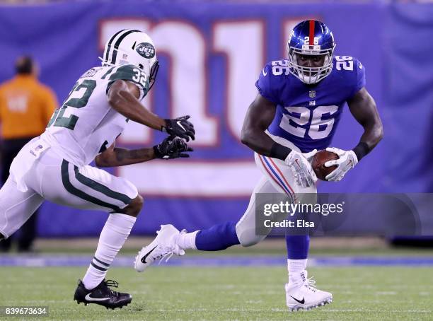 Orleans Darkwa of the New York Giants carries the ball as Juston Burris of the New York Jets defends during a preseason game on August 26, 2017 at...
