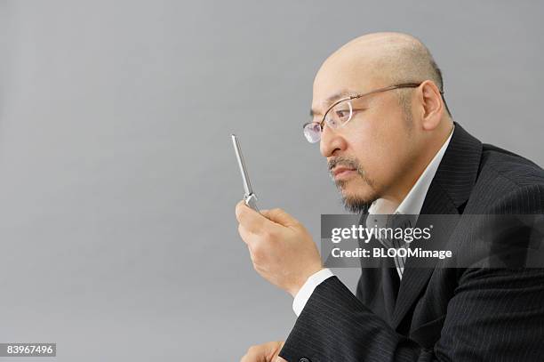 portrait of mature man using cellular phone, close up, in profile, studio shot - portrait close up loosely stock pictures, royalty-free photos & images