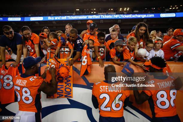 Lutside Linebacker Von Miller of the Denver Broncos, Darian Stewart and Demaryius Thomas sign autographs for fans during a Preseason game against the...