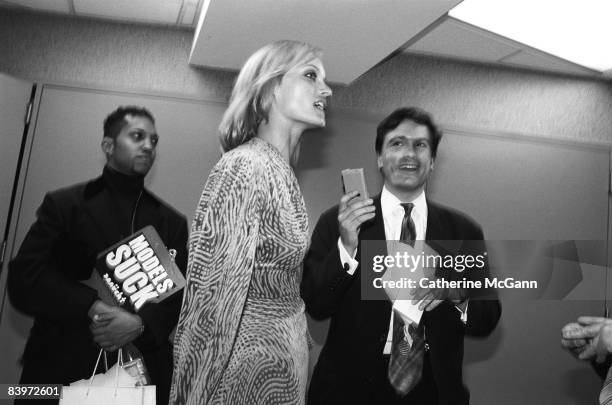 American supermodel Amber Valletta, center, walks past a person displaying a clipboard bearing a sticker which states "Models Suck" backstage at the...