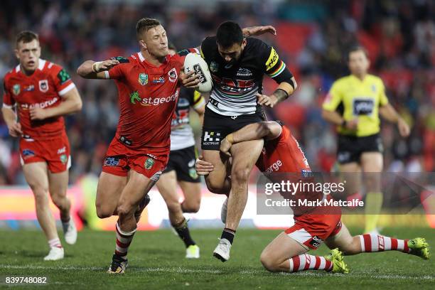 Tyrone May of the Panthers is tackled by Josh McCrone and Tariq Sims of the Dragons during the round 25 NRL match between the Penrith Panthers and...