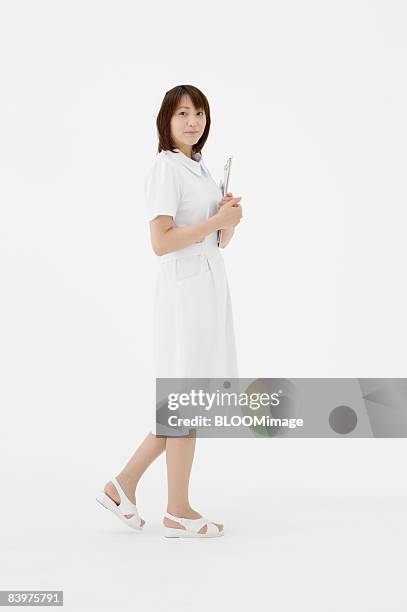 portrait of nurse holding clipboard, studio shot - nurse and portrait and white background and smiling and female and looking at camera stock pictures, royalty-free photos & images