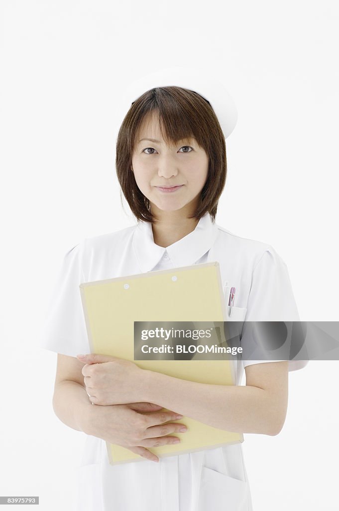 Portrait of nurse holding clipboard, studio shot