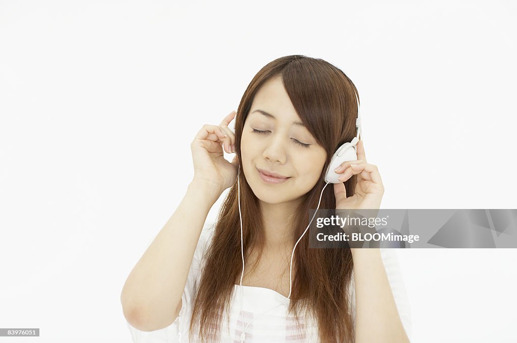 Woman listening to music with headphones, studio shot