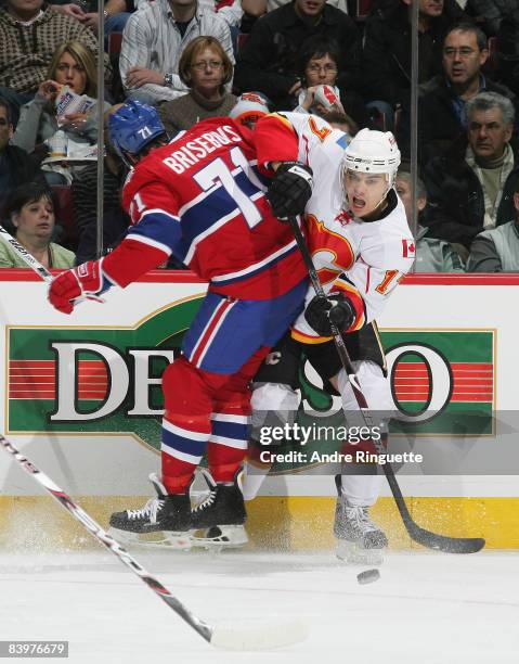 Patrice Brisebois of the Montreal Canadiens throws a bodyscheck as Georges Laraque of the Calgary Flames passes the puck at the Bell Centre on...