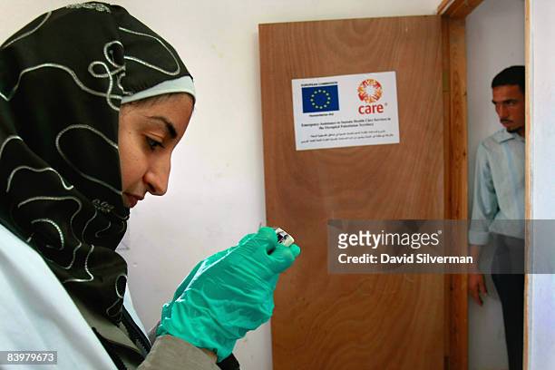 Palestinian lab technician Fidaa Taheneh prepares a vial as she takes blood from local schoolchildren for a hemoglobin test at a mobile clinic...