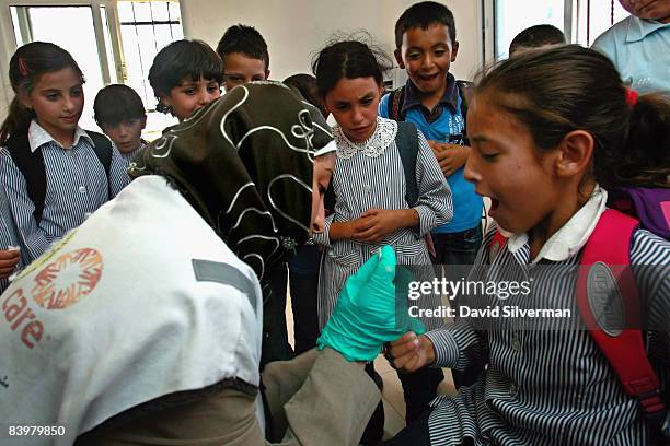 Palestinian lab technician Fidaa Taheneh takes blood from a local schoolgirl for a hemoglobin test at a mobile clinic provided by CARE International...