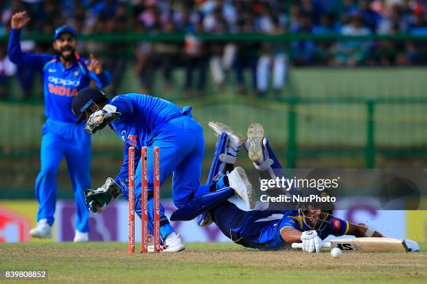 Sri Lankan cricketer Dinesh Chandimal dives in to survive a runout as India's wicket keeper MS Dhoni removes the bails during the 3rd One Day...