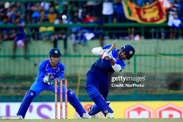 Sri Lankan cricketer Lahiru Thirimanne plays a shot for a boundary as Indian wicket keeper MS Dhoni looks on during the 3rd One Day International...