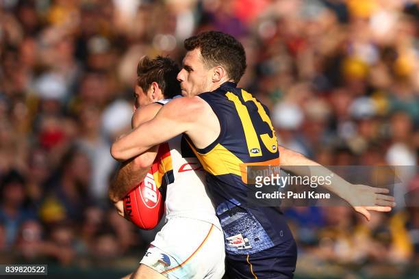 Luke Shuey of the Eagles tackles Richard Douglas of the Crows during the round 23 AFL match between the West Coast Eagles and the Adelaide Crows at...